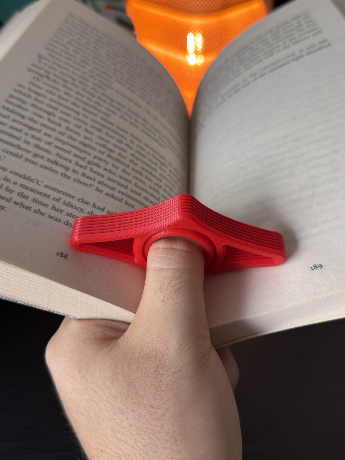 Red 3D printed book page holder used while reading