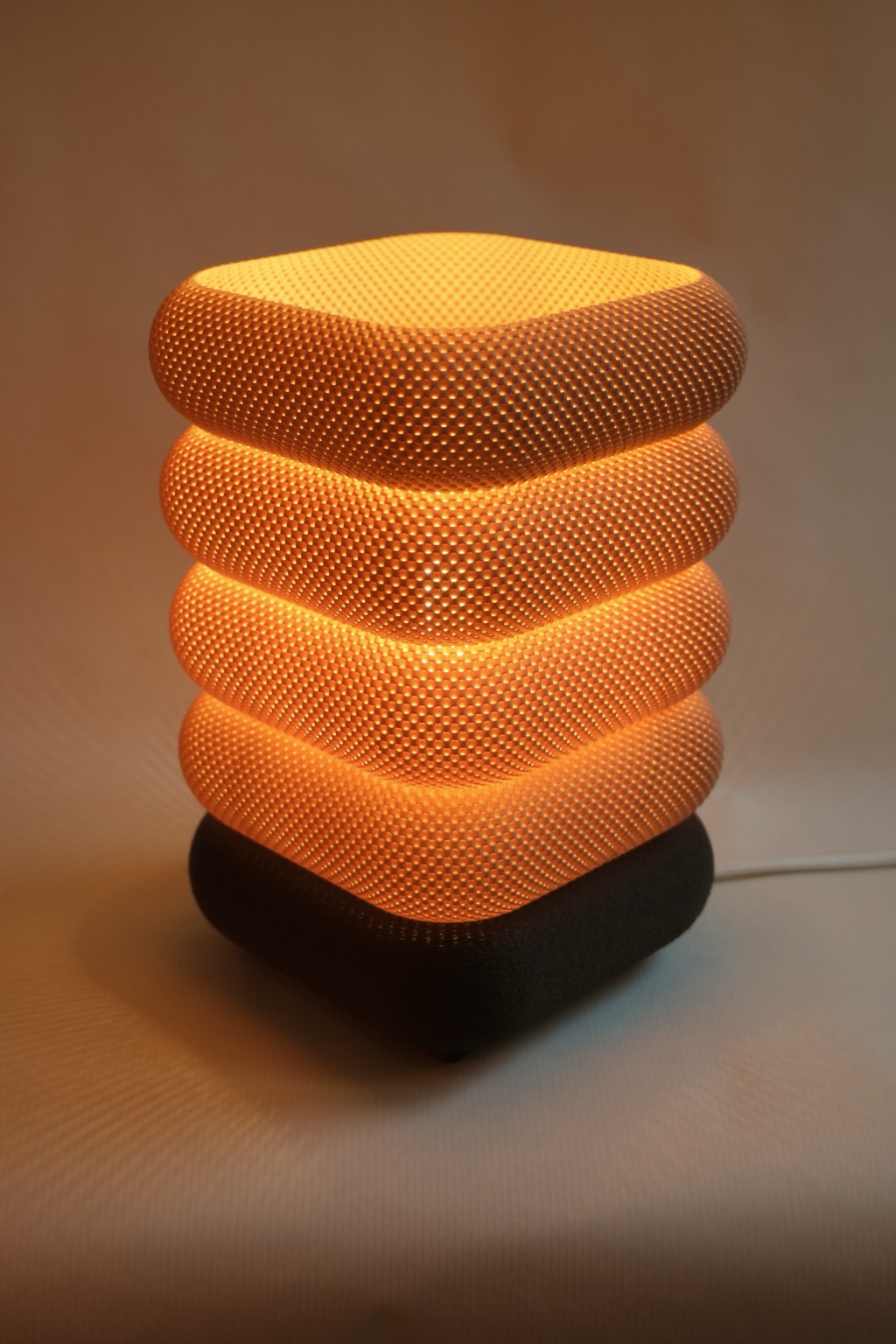 Warm orange Nobu3D 3D printed lamp glowing on a black base